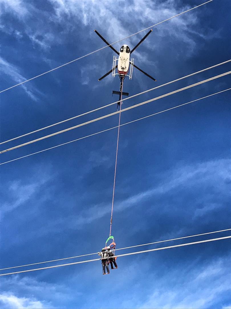 Helicopter on a longline placing linemen on power lines